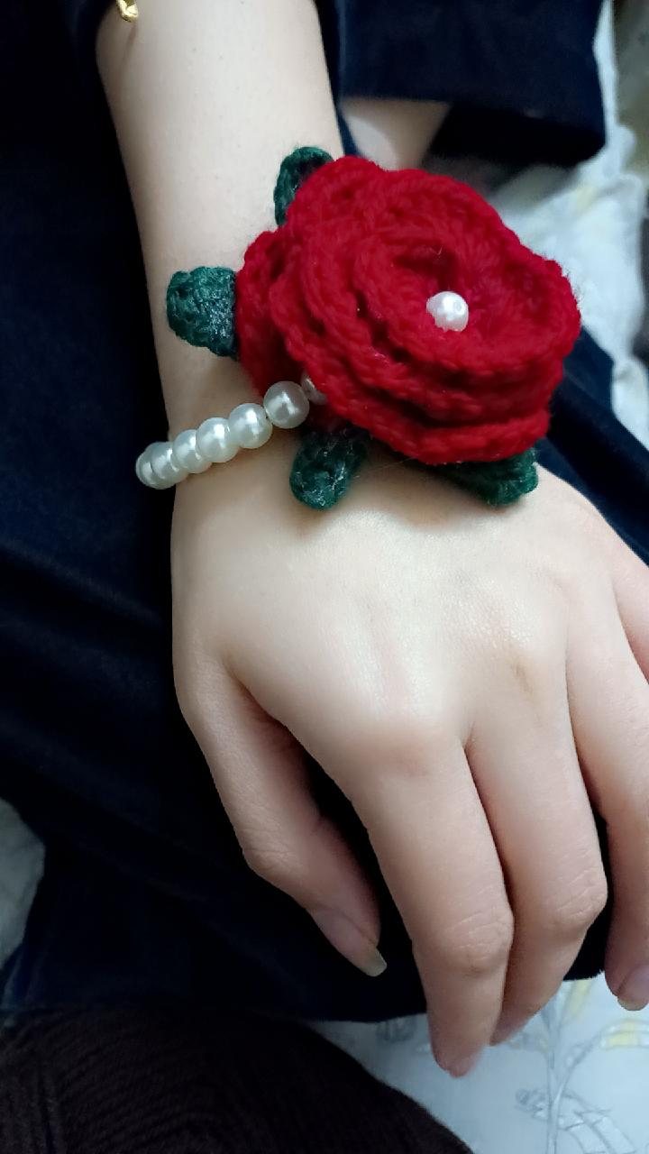 Hands holding a handmade crochet rose corsage